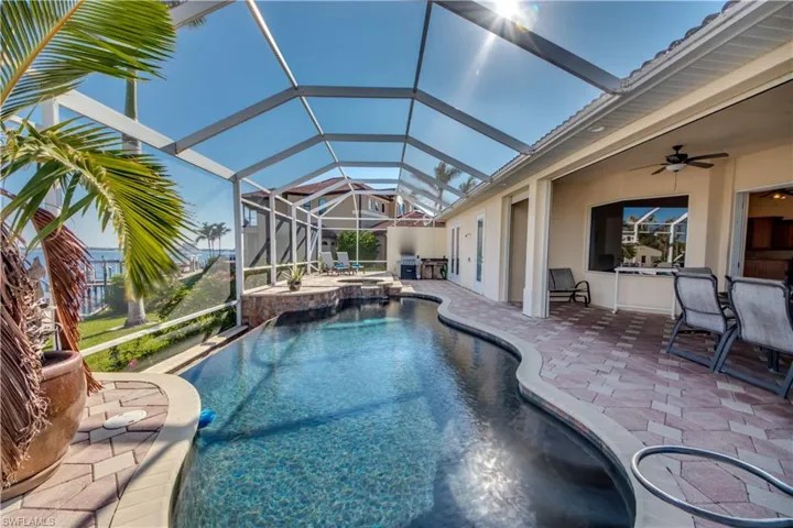 View of pool with an in ground hot tub, a patio, glass enclosure, and ceiling fan