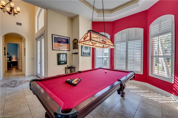 Recreation room featuring tile patterned floors, crown molding, a tray ceiling, and a high ceiling