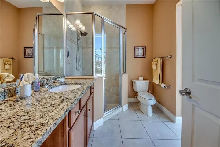 Bathroom with tile patterned floors, toilet, vanity, and walk in shower