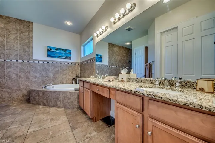 Bathroom with tile patterned floors, vanity, separate shower and tub, and tile walls