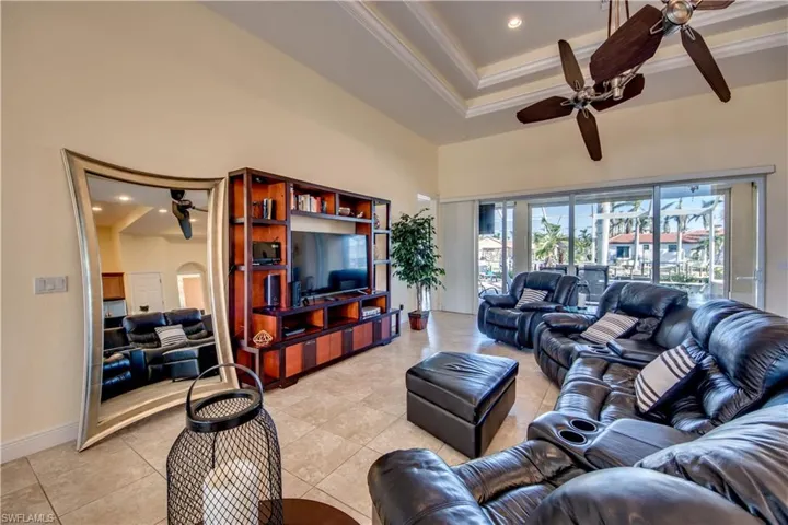 Living room featuring ceiling fan, light tile patterned floors, ornamental molding, and a towering ceiling