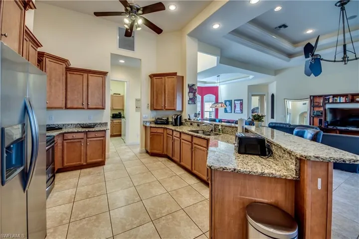 Kitchen featuring ceiling fan, sink, a breakfast bar, appliances with stainless steel finishes, and ornamental molding