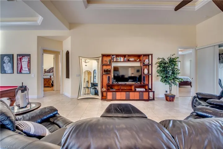 Living room with a raised ceiling, light tile patterned floors, and ornamental molding