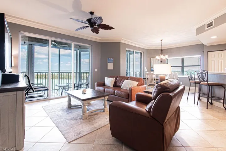 Living area with crown molding, a chandelier, light tile patterned flooring, and a water view