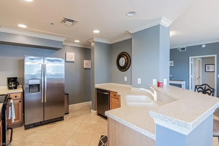 Kitchen featuring stainless steel appliances, a peninsula, crown molding, light tile patterned flooring, and recessed lighting