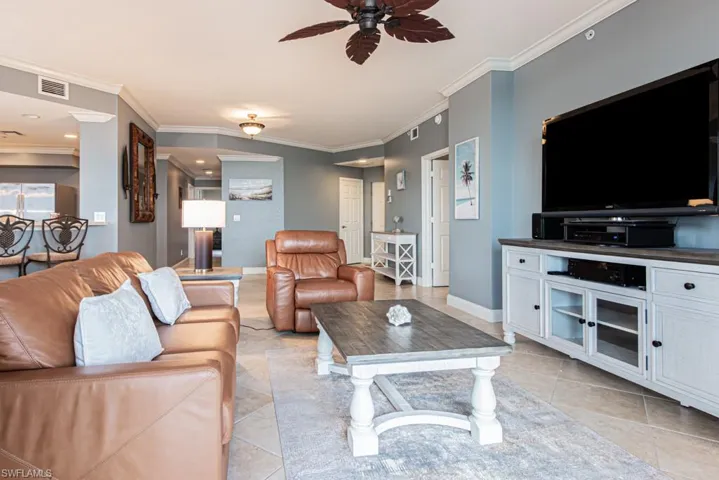 Living area with a ceiling fan, crown molding, and light tile patterned floors