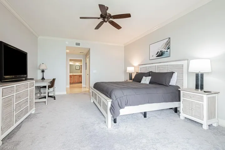 Bedroom featuring light colored carpet, ornamental molding, and ceiling fan