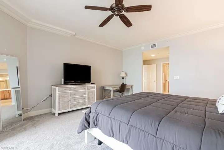 Carpeted bedroom with ornamental molding and ceiling fan