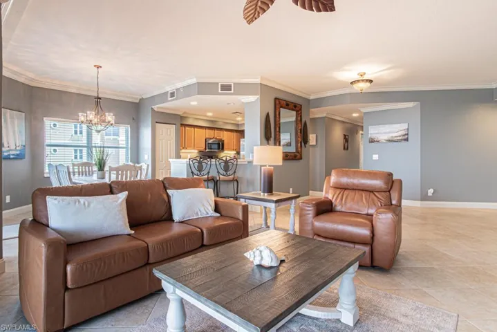 Living room with a chandelier, crown molding, light tile patterned flooring, recessed lighting, and ceiling fan
