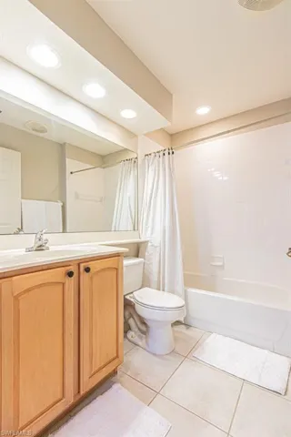 Bathroom featuring vanity, light tile patterned floors, shower / tub combo, and recessed lighting
