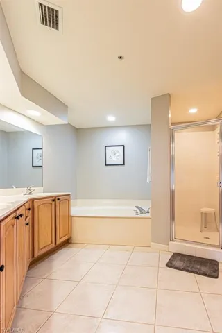 Bathroom featuring a bath, vanity, light tile patterned floors, a shower stall, and recessed lighting