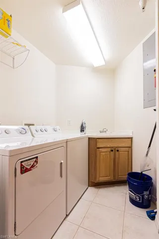 Washroom featuring light tile patterned floors, a textured ceiling, separate washer and dryer, cabinet space, and electric panel