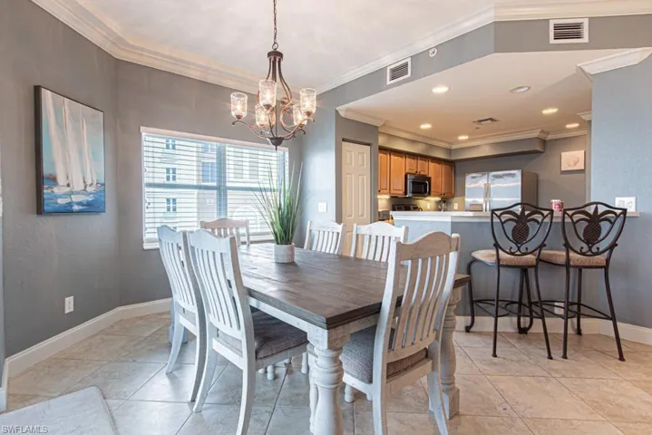 Dining space featuring ornamental molding, a chandelier, a textured wall, and light tile patterned floors