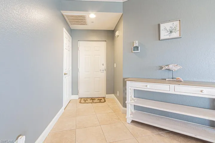Doorway with a textured wall and tile patterned floors