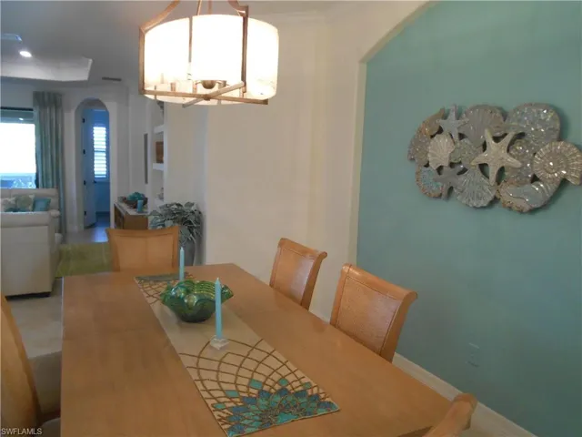 Dining room with a chandelier, arched walkways, and crown molding
