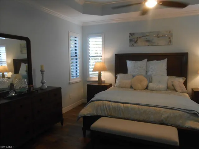 Bedroom with ornamental molding, dark wood-style flooring, and ceiling fan