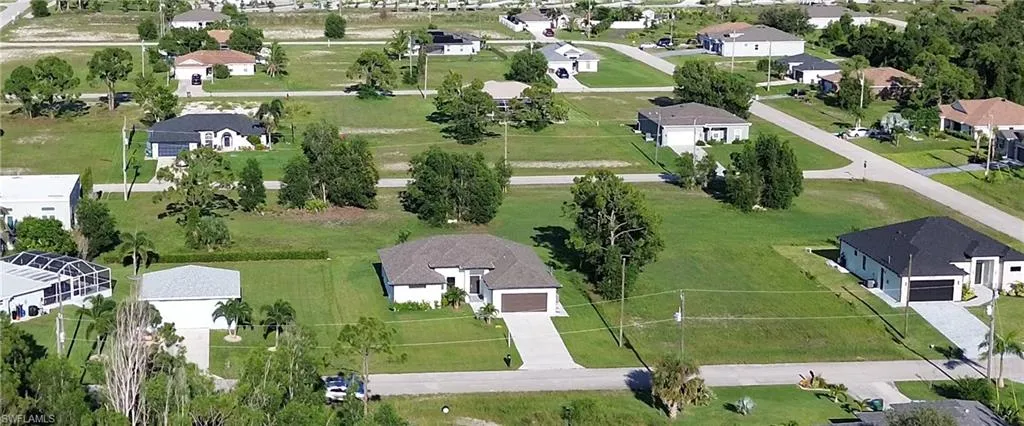 Aerial perspective highlighting a single-story residence with a light-colored exterior and an attached garage