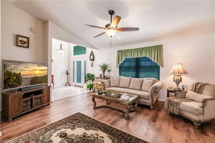Living room featuring lofted ceiling, ceiling fan, and hardwood / wood-style floors