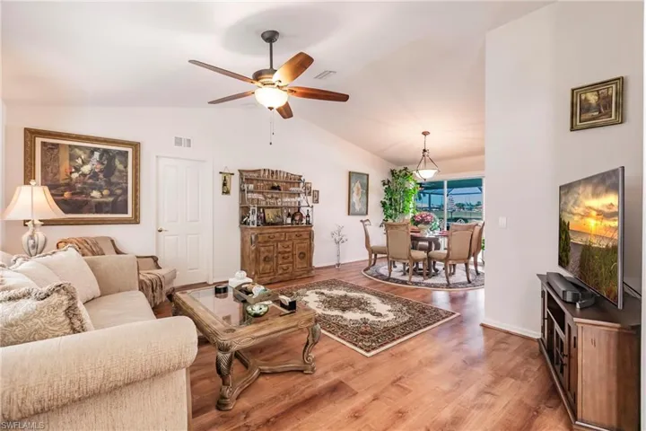 Living room with ceiling fan, lofted ceiling, and wood-type flooring