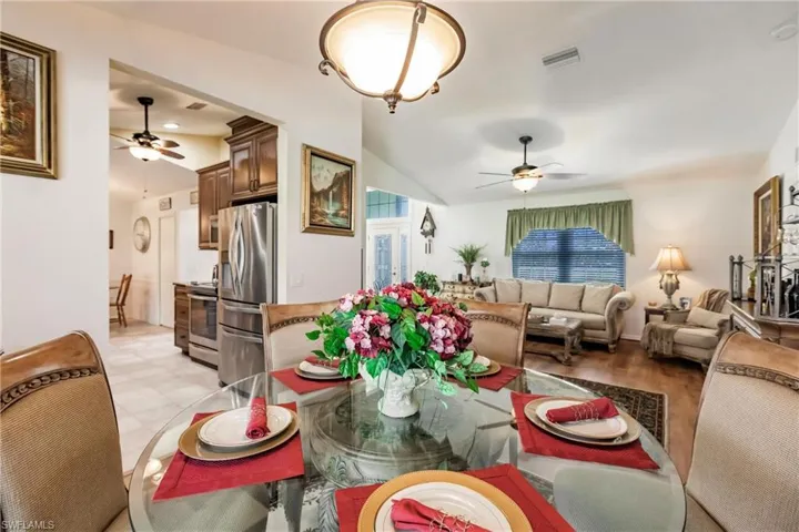 Dining space featuring ceiling fan, light tile flooring, and lofted ceiling