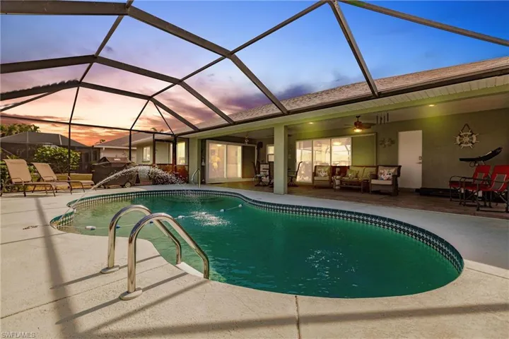 Pool at dusk featuring ceiling fan, glass enclosure, and a patio area