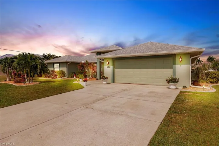 View of front facade featuring a garage and a yard