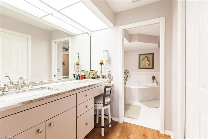 Bathroom with tile flooring, a relaxing tiled bath, and vanity