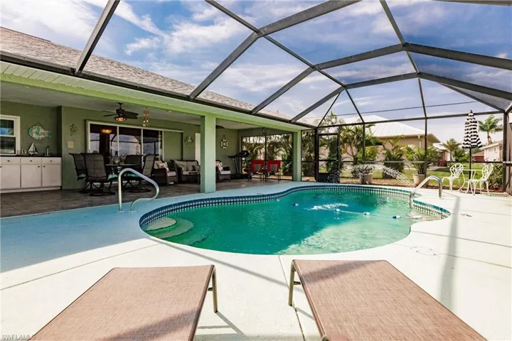 View of pool with a lanai, a patio area, and ceiling fan