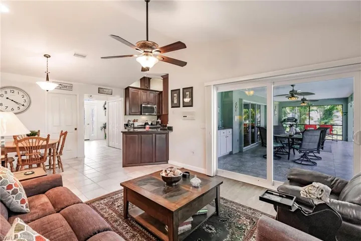 Living room featuring ceiling fan, light tile flooring, and lofted ceiling