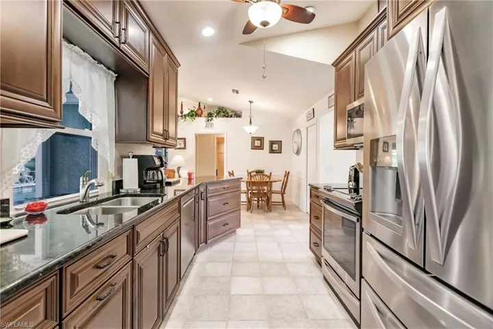 Living room with tile floors, lofted ceiling, and ceiling fan