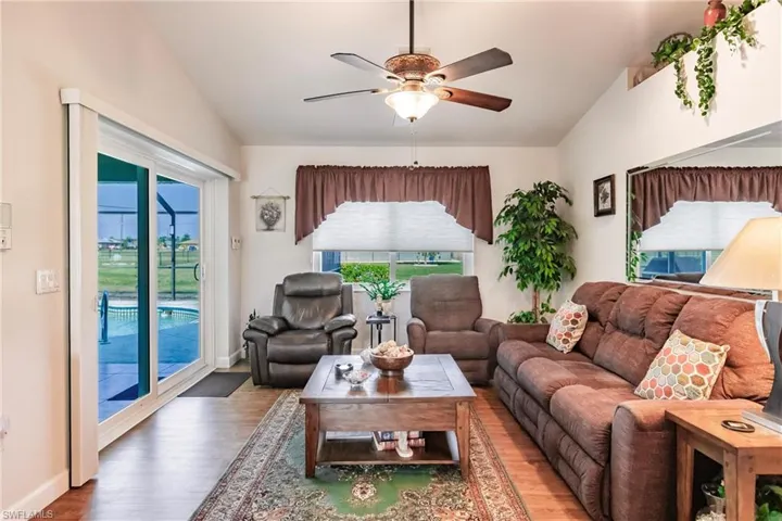 Living room featuring ceiling fan, hardwood / wood-style floors, and lofted ceiling