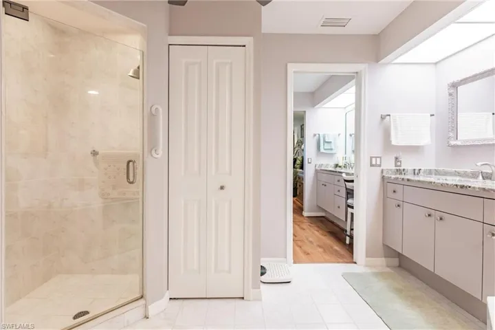 Bathroom featuring vanity with extensive cabinet space, an enclosed shower, and tile flooring