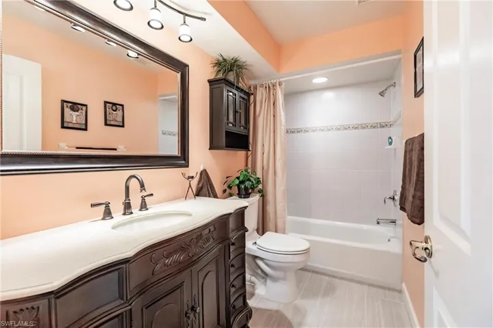 Full bathroom featuring shower / bath combo with shower curtain, vanity, toilet, and tile floors