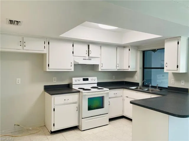 Kitchen featuring white cabinetry, sink, and white range with electric stovetop
