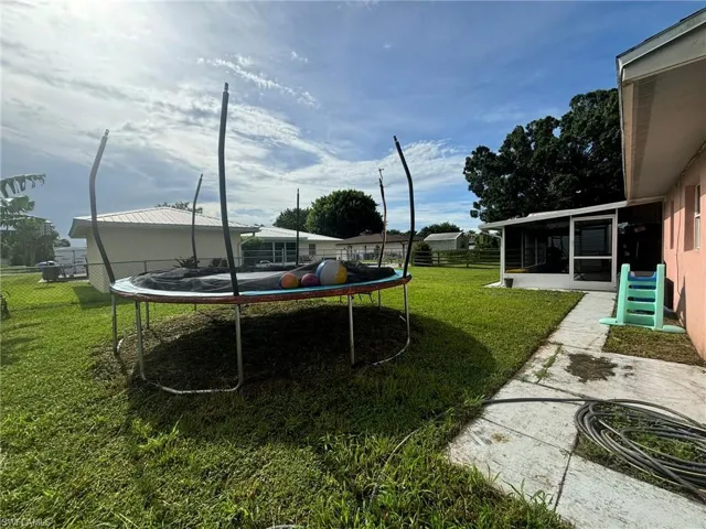 View of yard featuring a sunroom and a trampoline