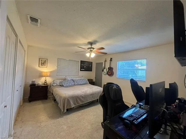 Bedroom featuring a textured ceiling, light carpet, ceiling fan, and a closet
