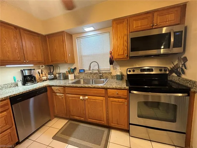 Kitchen featuring, tile flooring, stainless steel appliances, dark stone counters, and ceiling fan