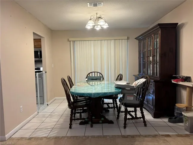 Tiled dining room featuring an inviting chandelier