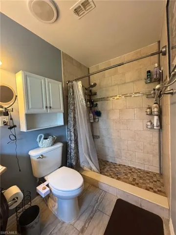 Bathroom featuring walk in shower, tile patterned flooring, and toilet