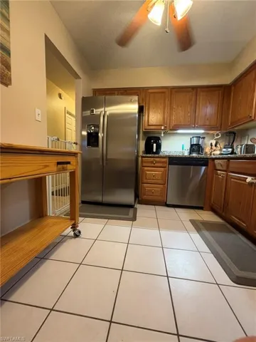 Kitchen featuring, tile flooring, stainless steel appliances, dark stone counters, and ceiling fan