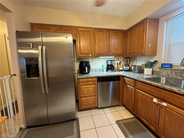 Kitchen featuring, tile flooring, stainless steel appliances, dark stone counters, and ceiling fan