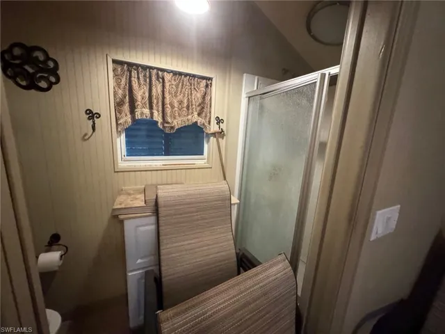 Bathroom featuring lofted ceiling, toilet, and a shower with shower door