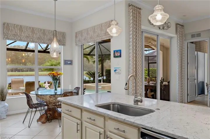 Kitchen featuring a healthy amount of sunlight, sink, light stone counters, and crown molding