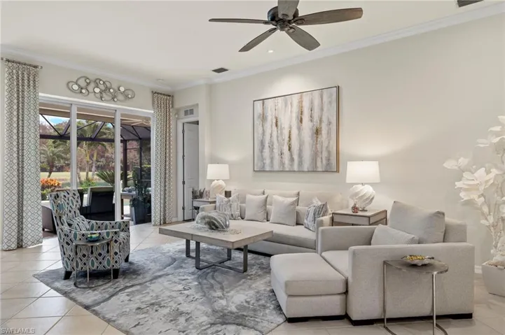 Living room featuring light tile patterned flooring, ceiling fan, and ornamental molding