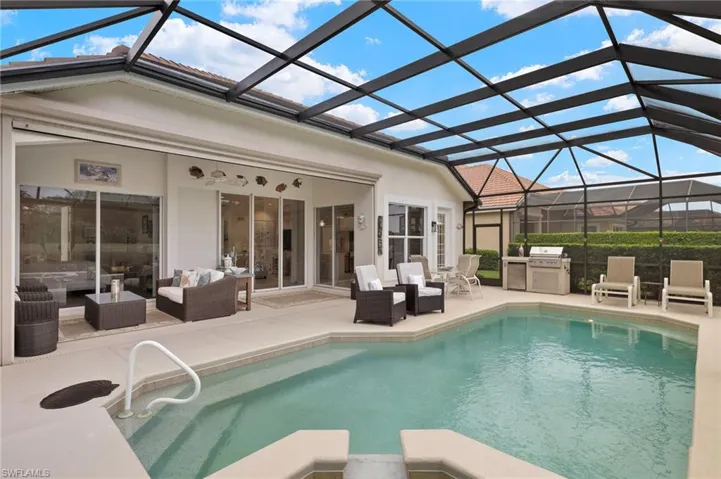 View of pool featuring ceiling fan, a patio area, glass enclosure, and an outdoor living space