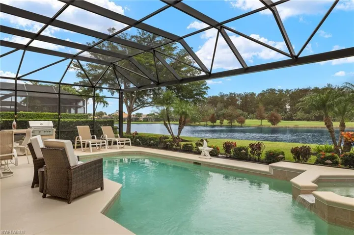 View of swimming pool featuring a water view, an in ground hot tub, a patio area, a grill, and glass enclosure