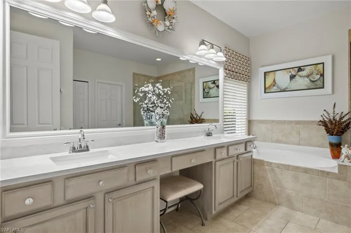 Bathroom featuring tile patterned flooring, shower with separate bathtub, and vanity