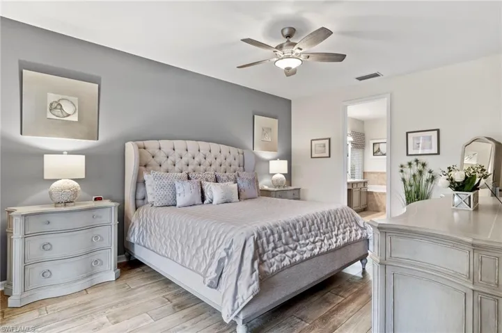 Bedroom featuring ceiling fan, ensuite bath, and light wood-type flooring
