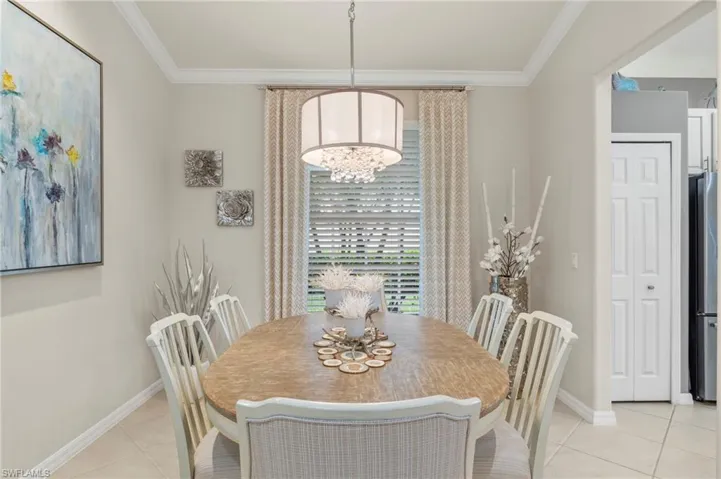 Tiled dining room featuring ornamental molding and a notable chandelier