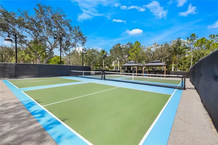 View of tennis court featuring basketball hoop and a gazebo